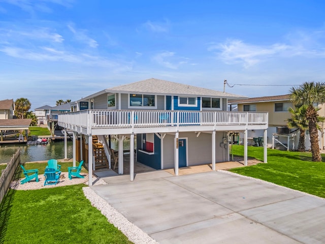 view of front of house with a deck with water view, a front yard, and a patio area