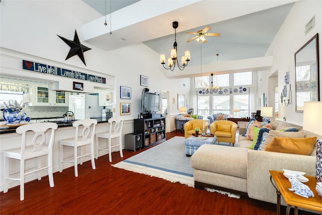 living room featuring dark wood-type flooring, ceiling fan with notable chandelier, high vaulted ceiling, and a healthy amount of sunlight