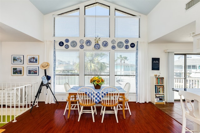 dining area with high vaulted ceiling and dark hardwood / wood-style flooring