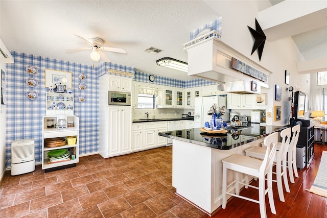 kitchen featuring white appliances, white cabinets, sink, and kitchen peninsula