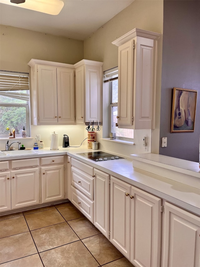 kitchen featuring light tile flooring, sink, and white cabinets