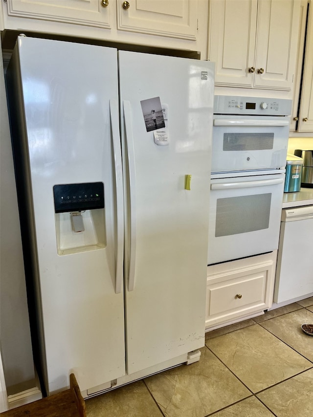 kitchen with white appliances, light tile floors, and white cabinets