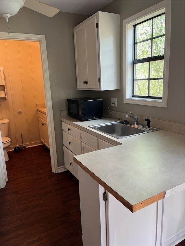 kitchen with white cabinets, dark hardwood / wood-style floors, kitchen peninsula, ceiling fan, and sink