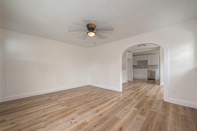 empty room with ceiling fan, light wood-type flooring, and sink