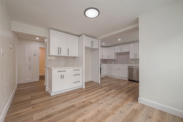 kitchen with white cabinetry, light hardwood / wood-style floors, sink, stainless steel dishwasher, and tasteful backsplash