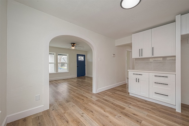 kitchen with backsplash, white cabinetry, ceiling fan, and light hardwood / wood-style flooring