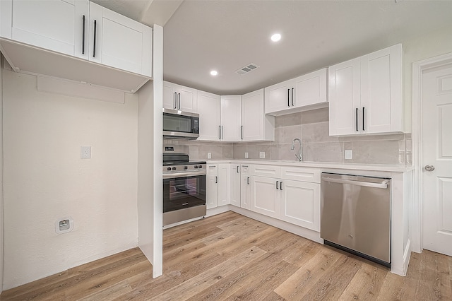 kitchen featuring light hardwood / wood-style flooring, stainless steel appliances, backsplash, and white cabinets