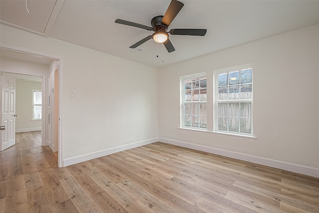 spare room featuring ceiling fan, light wood-type flooring, and a wealth of natural light