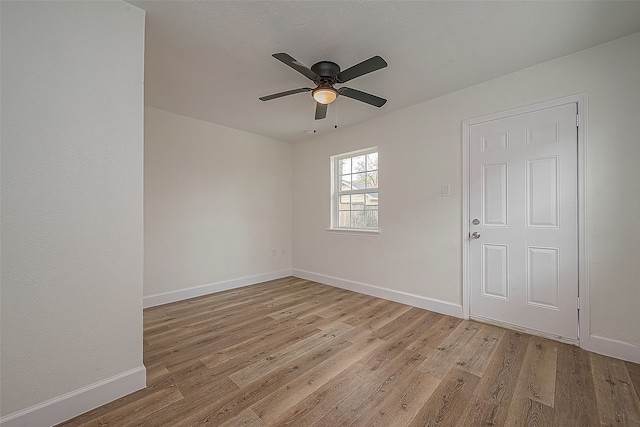 empty room with ceiling fan and light hardwood / wood-style flooring