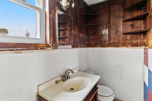 bathroom featuring tile walls, backsplash, toilet, and vanity with extensive cabinet space