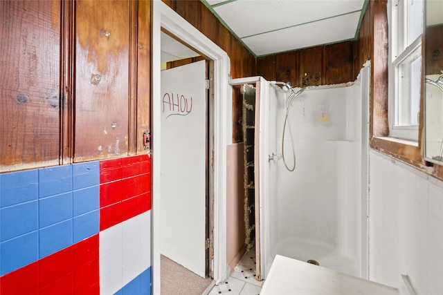 bathroom featuring wooden walls, tile flooring, and a shower