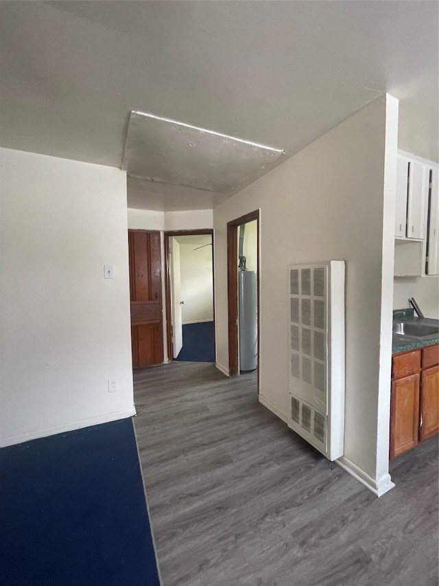 unfurnished room with sink, dark hardwood / wood-style floors, and water heater