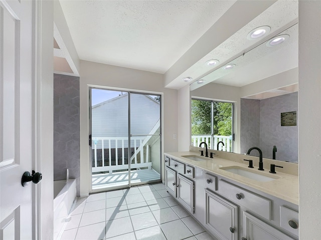 bathroom featuring tile flooring, dual vanity, a bathing tub, and a textured ceiling