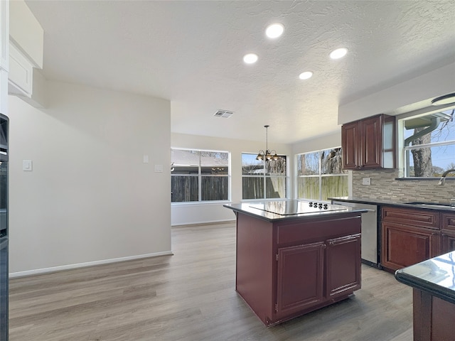 kitchen with a kitchen island, sink, a chandelier, and light hardwood / wood-style flooring