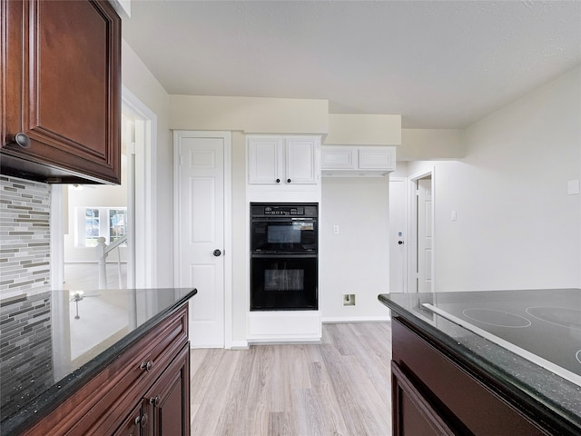 kitchen with electric stovetop, tasteful backsplash, dark brown cabinets, light hardwood / wood-style flooring, and black double oven