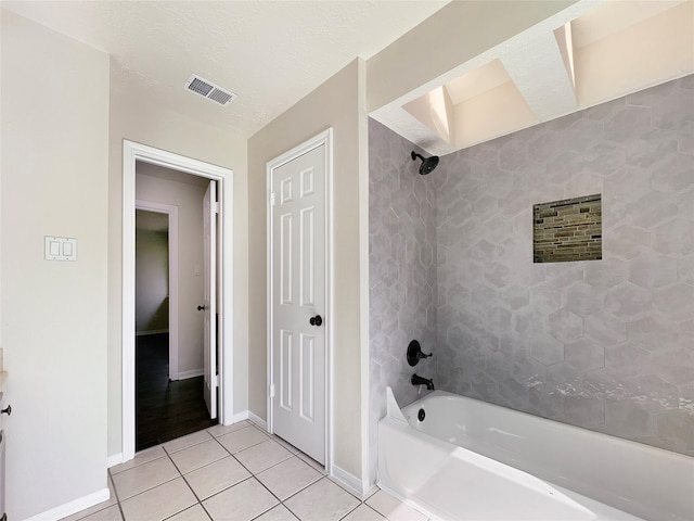 bathroom featuring tiled shower / bath combo, a textured ceiling, and tile floors