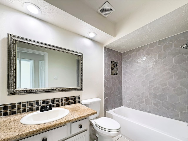 full bathroom with tiled shower / bath, toilet, vanity with extensive cabinet space, and tasteful backsplash