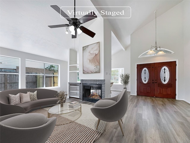 interior space with a healthy amount of sunlight, ceiling fan with notable chandelier, light hardwood / wood-style flooring, and a tiled fireplace