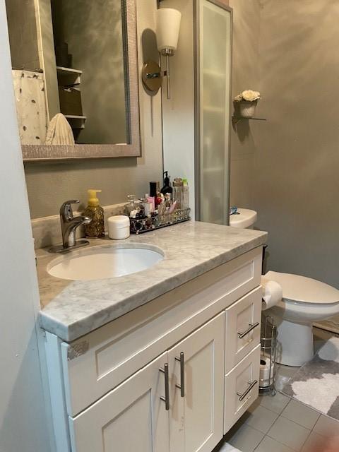 bathroom with tile patterned flooring, vanity, and toilet