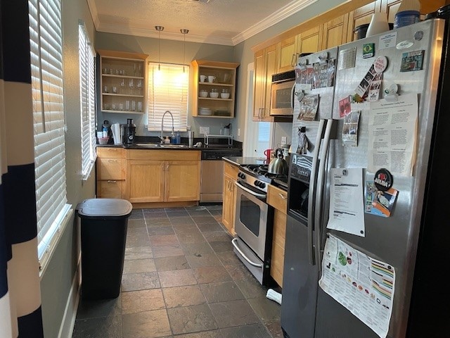 kitchen featuring light brown cabinetry, sink, stainless steel appliances, and decorative light fixtures