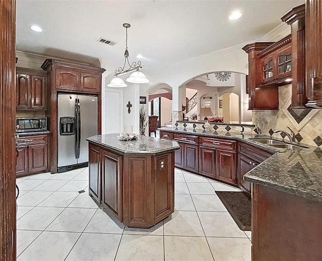 kitchen featuring light tile floors, dark stone counters, hanging light fixtures, appliances with stainless steel finishes, and tasteful backsplash