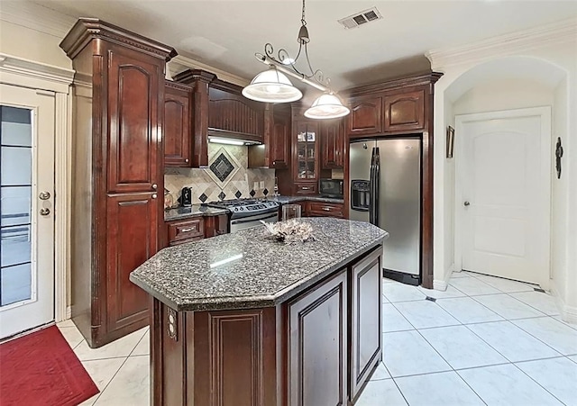 kitchen with pendant lighting, a center island, stainless steel fridge, backsplash, and gas stove