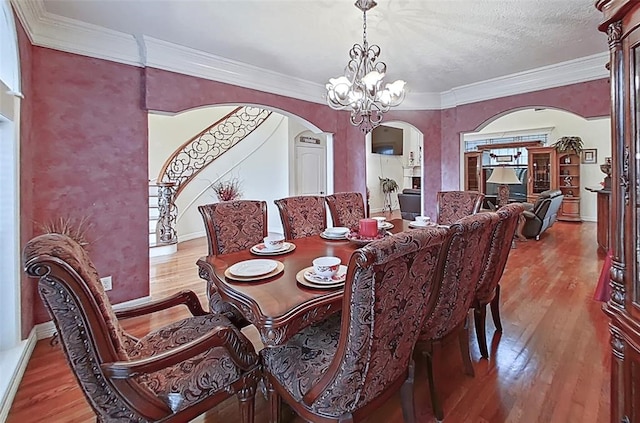 dining room featuring a chandelier, a textured ceiling, wood-type flooring, and crown molding