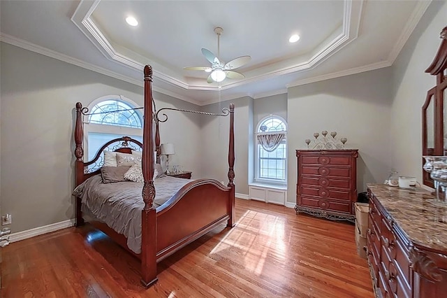 bedroom with ceiling fan, crown molding, a raised ceiling, and hardwood / wood-style flooring