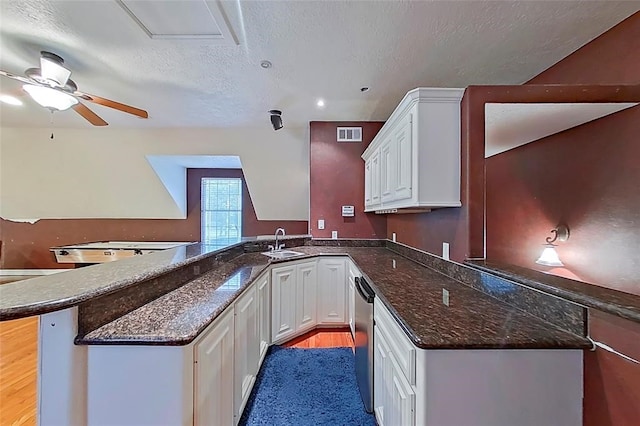 kitchen with dark stone counters, light wood-type flooring, ceiling fan, and kitchen peninsula