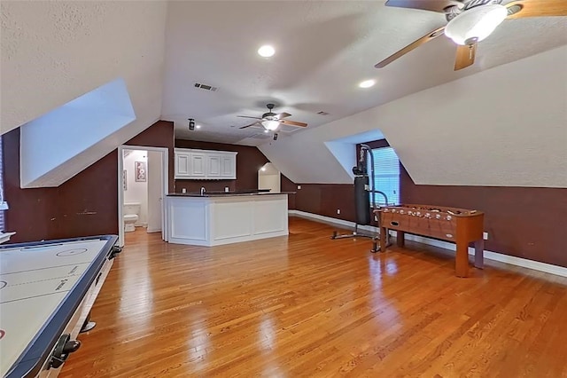 interior space with ceiling fan, vaulted ceiling, and light wood-type flooring