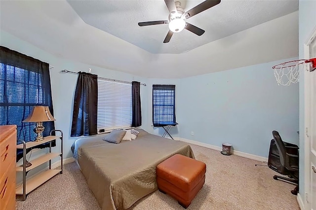 carpeted bedroom with ceiling fan and a tray ceiling