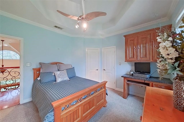 carpeted bedroom with a tray ceiling, ceiling fan, and crown molding