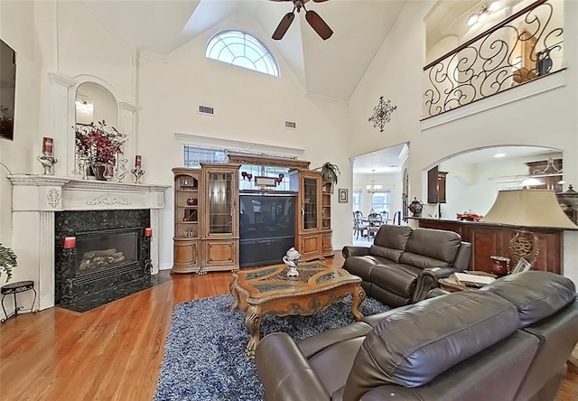 living room featuring ceiling fan, a premium fireplace, hardwood / wood-style flooring, and a wealth of natural light