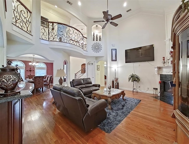 living room with high vaulted ceiling, hardwood / wood-style floors, and ceiling fan with notable chandelier