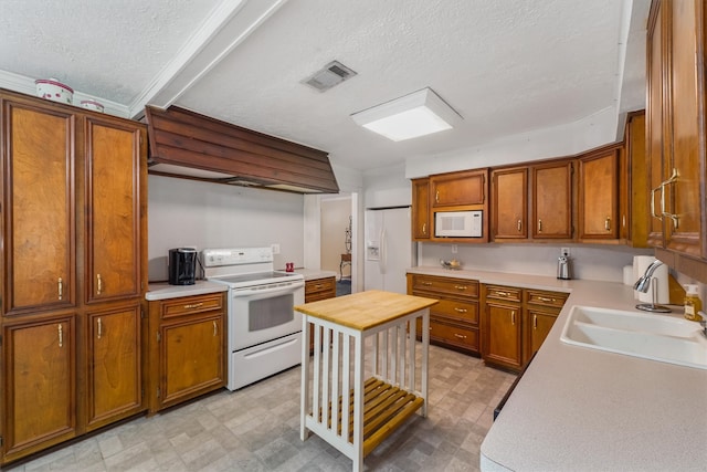 kitchen with a textured ceiling, white appliances, and sink