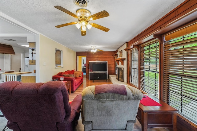 living room with a wealth of natural light, wood walls, light hardwood / wood-style floors, and a textured ceiling