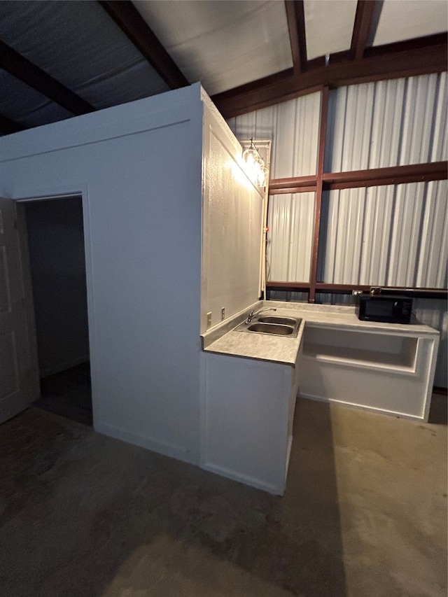 kitchen featuring beamed ceiling, sink, and white cabinetry