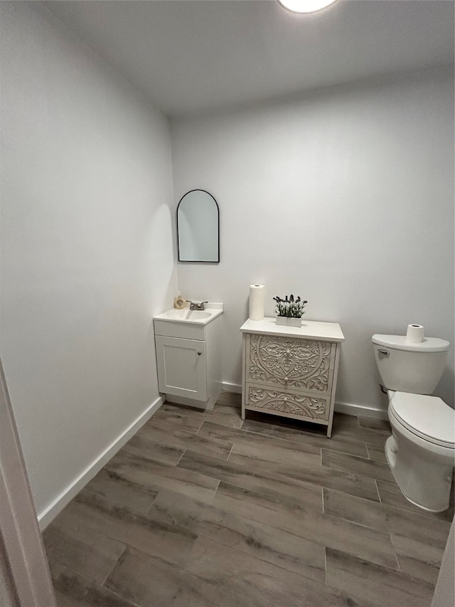 bathroom with hardwood / wood-style flooring, toilet, and vanity