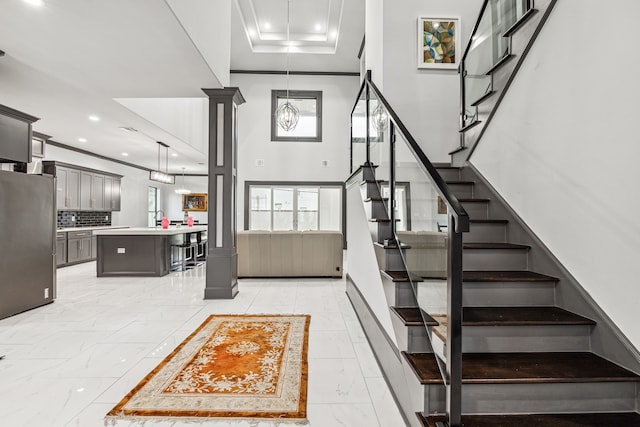 stairway featuring marble finish floor, recessed lighting, crown molding, and ornate columns