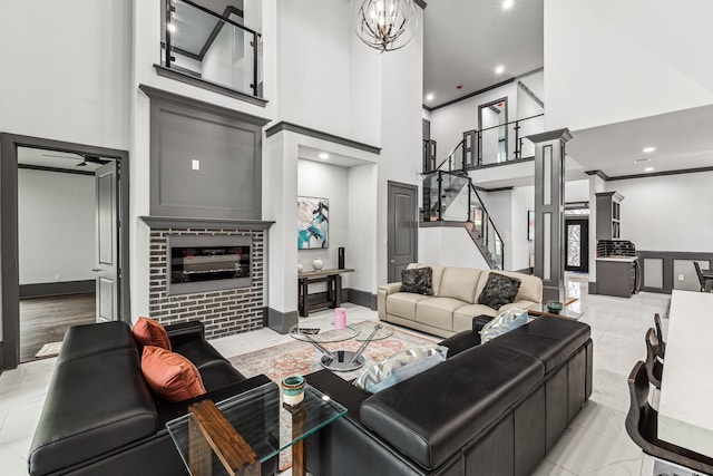 living room with stairway, a high ceiling, an inviting chandelier, ornamental molding, and a brick fireplace