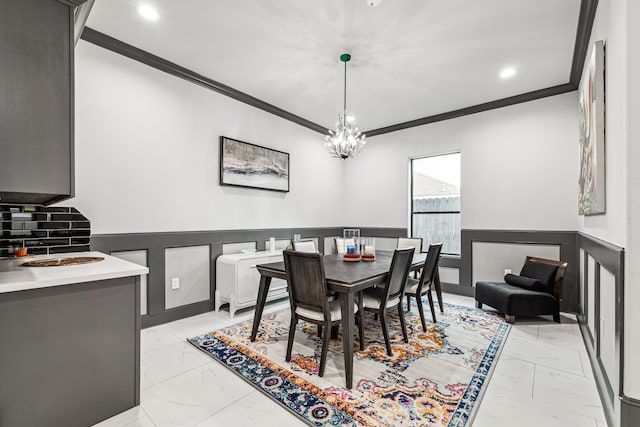 dining area featuring a wainscoted wall, marble finish floor, ornamental molding, and a chandelier