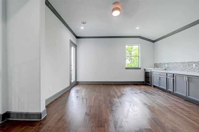 interior space featuring visible vents, ornamental molding, dark wood-type flooring, beverage cooler, and baseboards