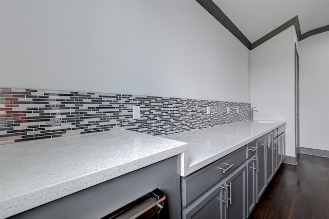 interior space featuring dark wood-type flooring, a sink, light stone countertops, gray cabinets, and backsplash