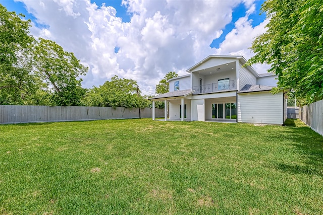 back of property with a fenced backyard, a yard, a balcony, and a patio