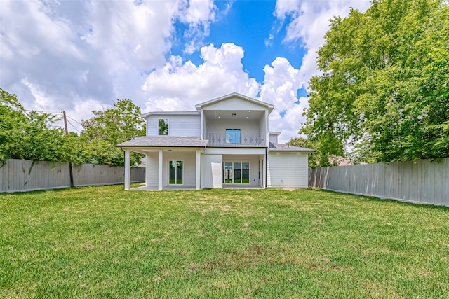 rear view of house with a patio, a lawn, a fenced backyard, and a balcony