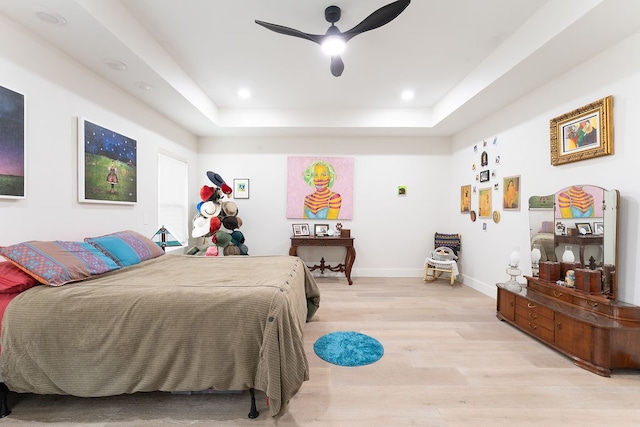 bedroom featuring a raised ceiling, ceiling fan, and light hardwood / wood-style floors