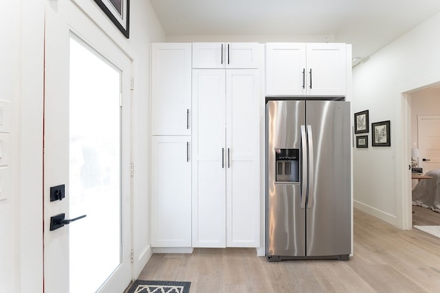 kitchen with white cabinets, stainless steel fridge, and light wood-type flooring