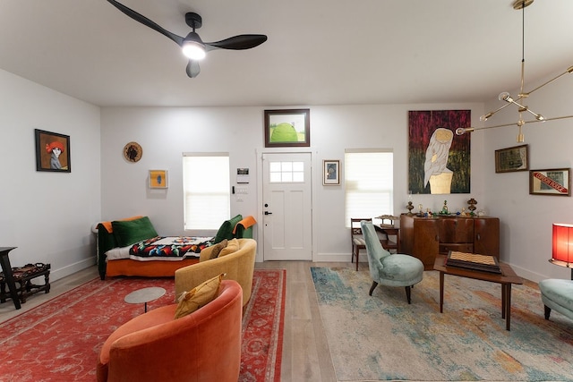 living room with ceiling fan with notable chandelier and light wood-type flooring