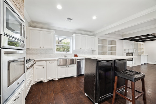 kitchen with appliances with stainless steel finishes, backsplash, white cabinets, dark hardwood / wood-style flooring, and ornamental molding