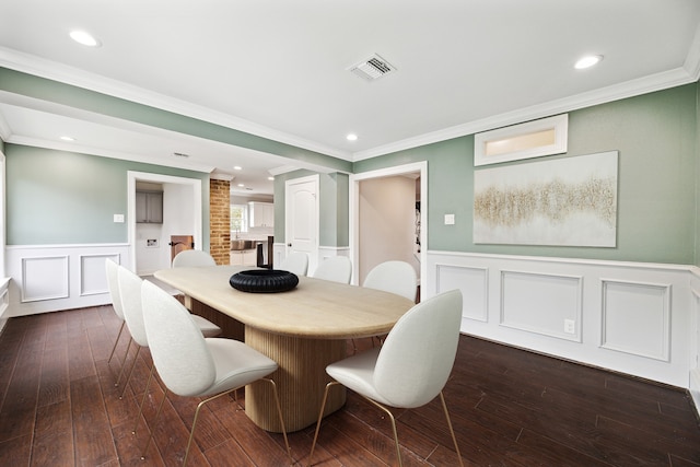 dining room featuring dark hardwood / wood-style flooring, crown molding, and brick wall